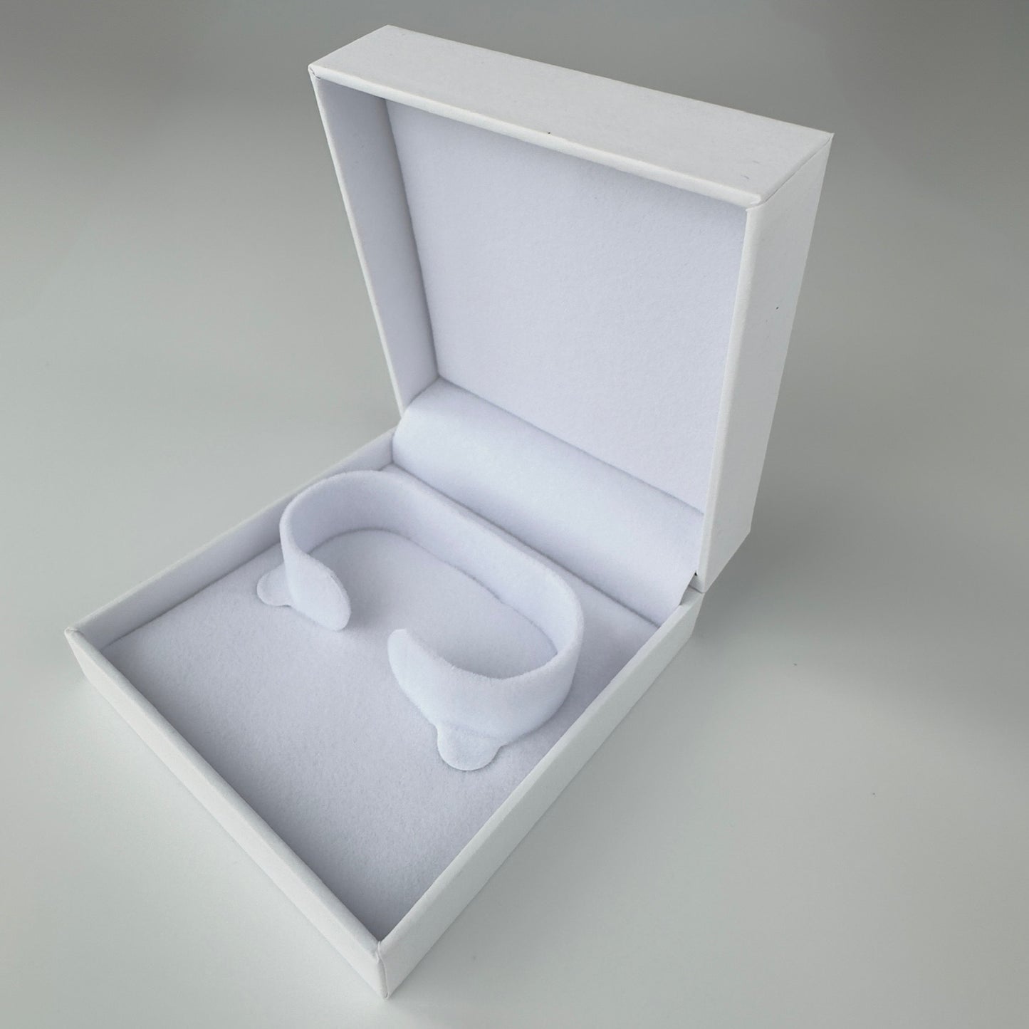 White earbuds in an open white box on a gray background