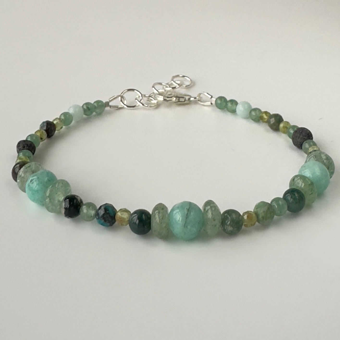 Beaded bracelet in shades of green on a light gray background