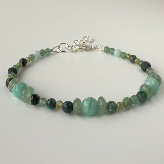 Beaded bracelet in shades of green on a light gray background