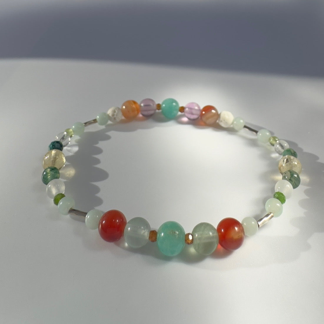 Beaded bracelet with orange yellow and green beads on a light gray background