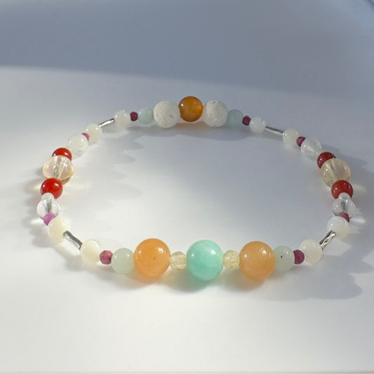 Beaded bracelet in tones of blue orange and white on a pale grey background