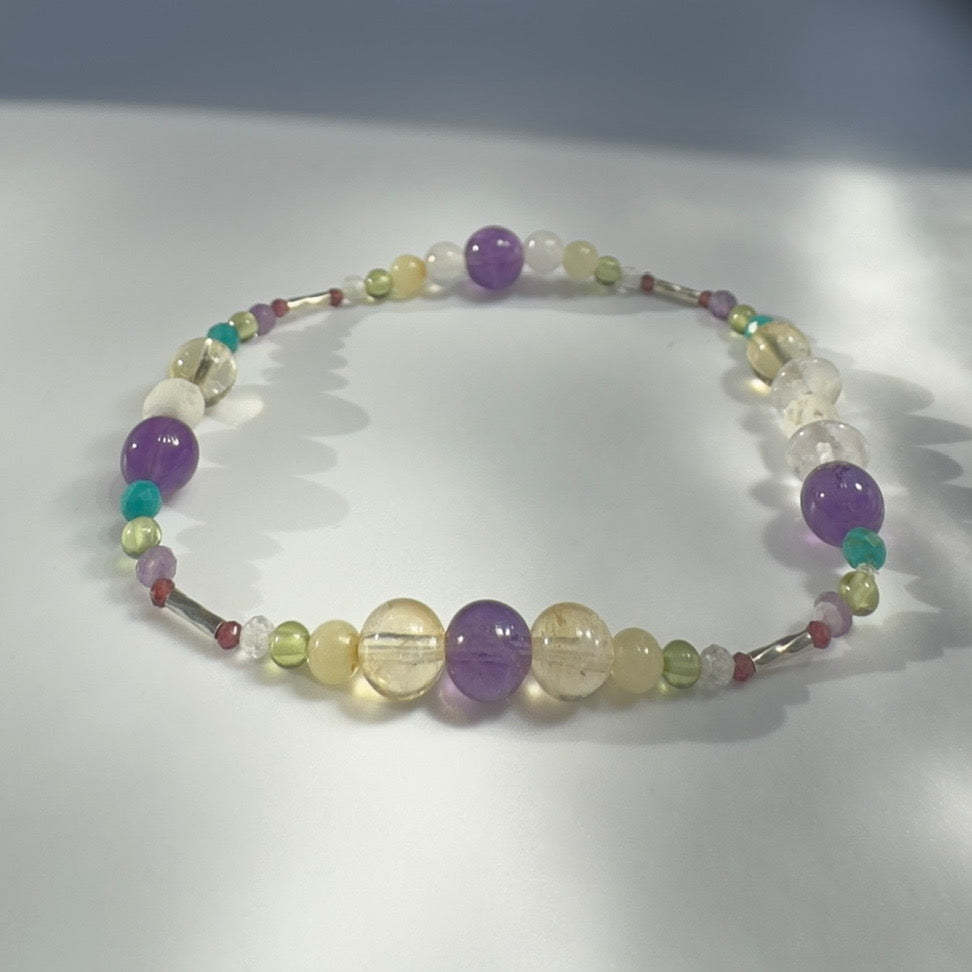 Beaded bracelet in yellow green and purple tones on a grey background 