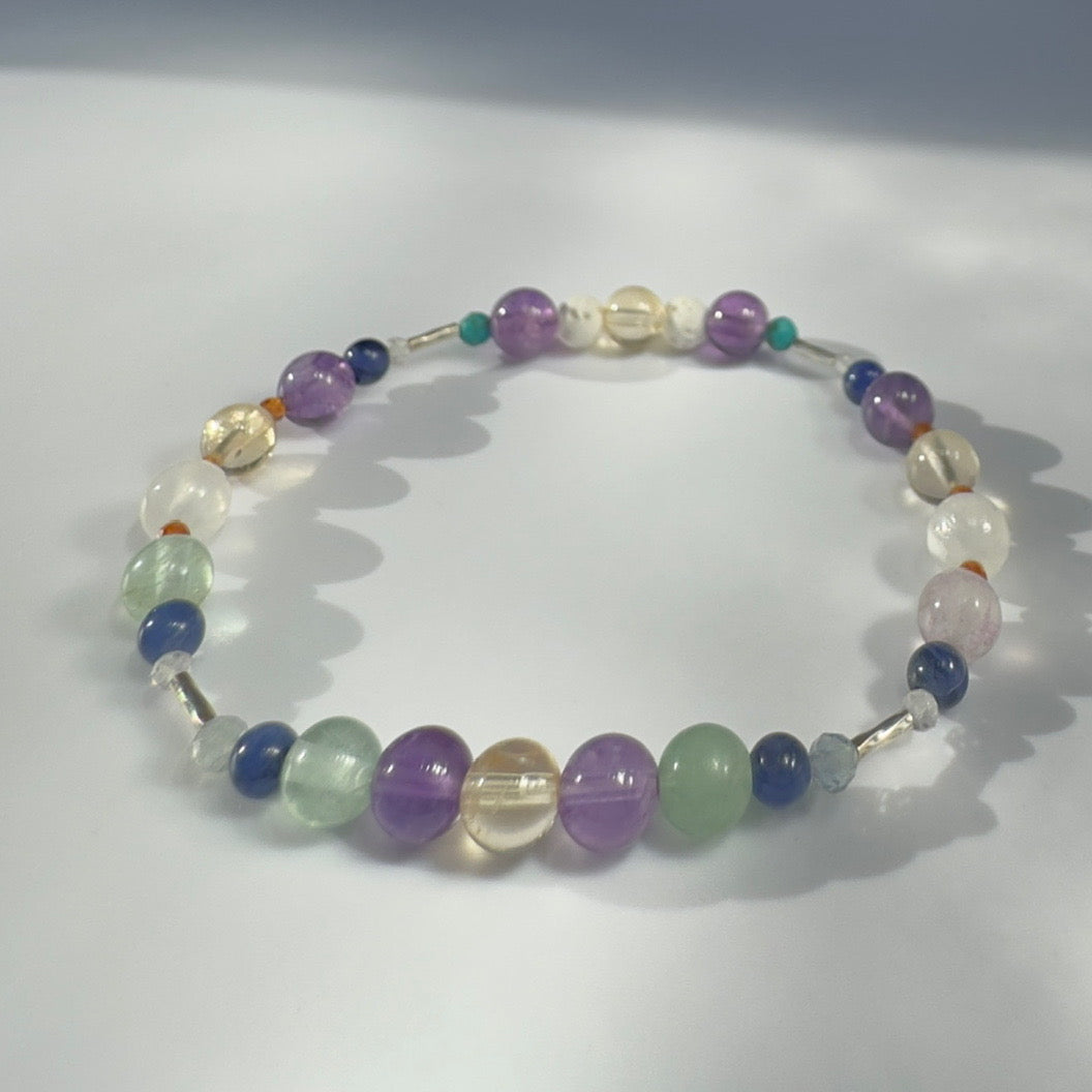 Beaded bracelet in yellow purple and green tones on a white background