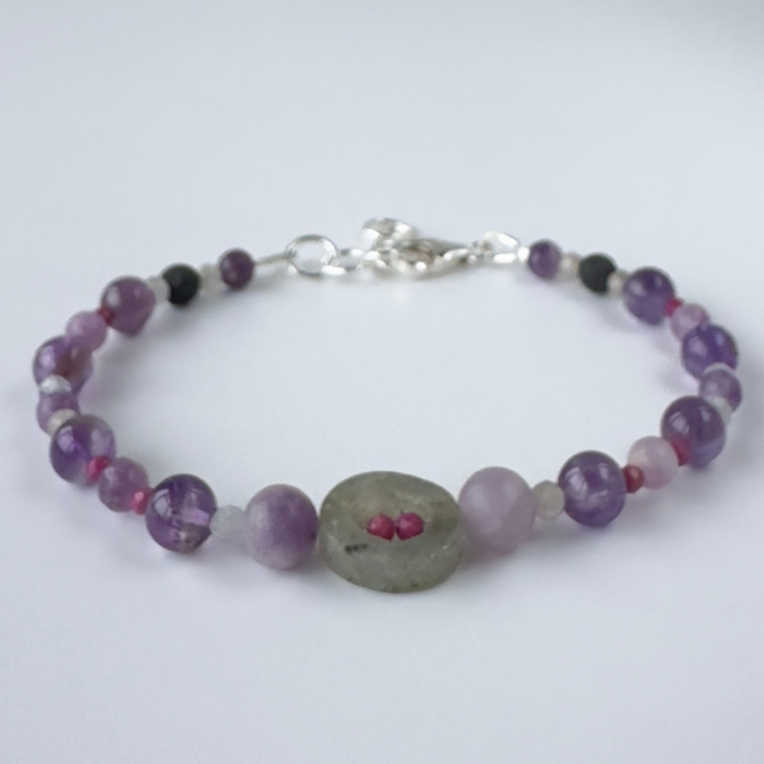 Purple and grey beaded bracelet on white background