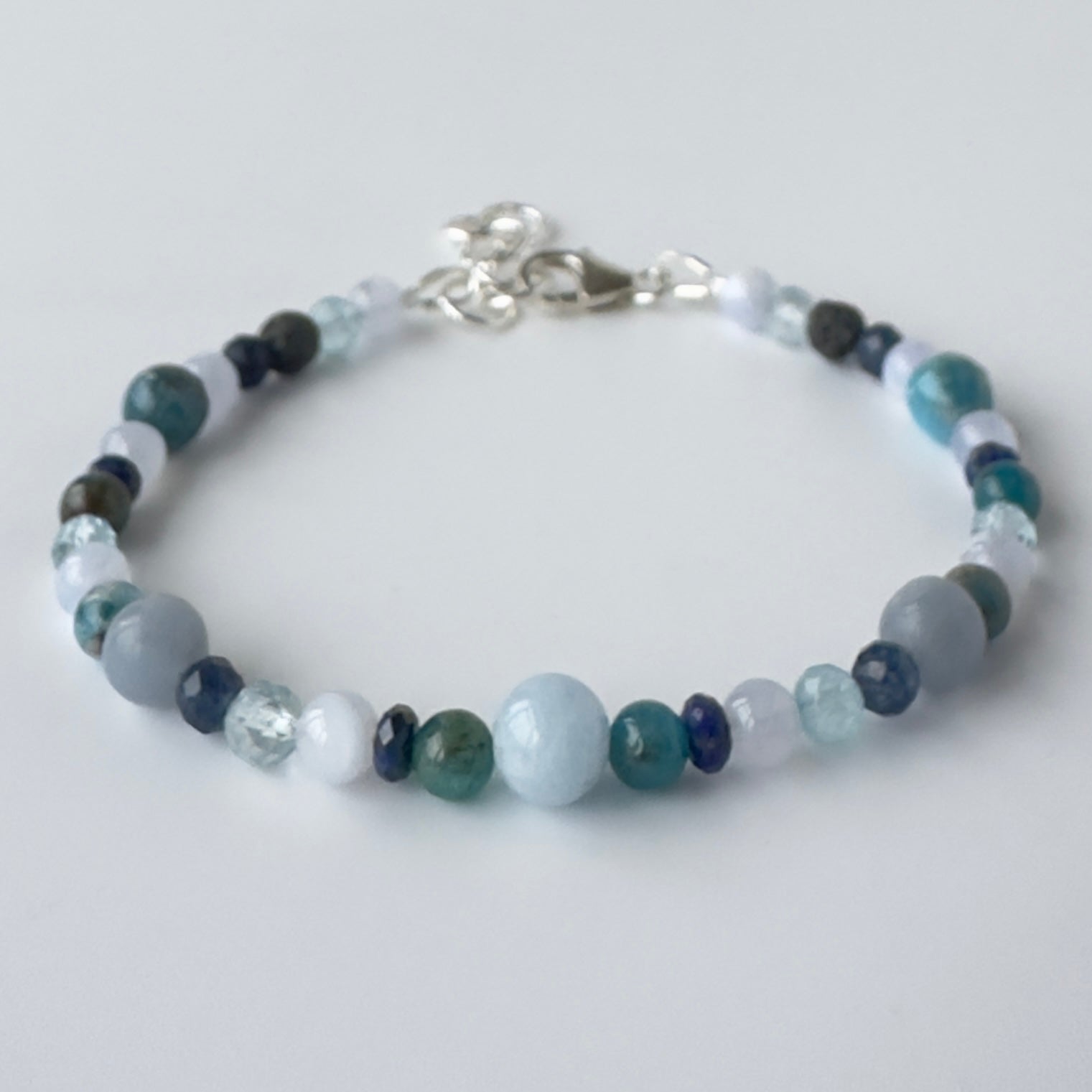 Beaded bracelet in shades of blue on a light grey background