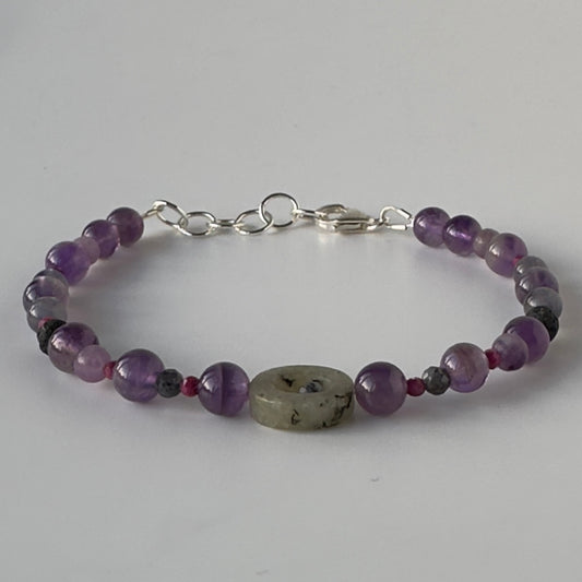 Beaded bracelet with purple and grey beads on a white background