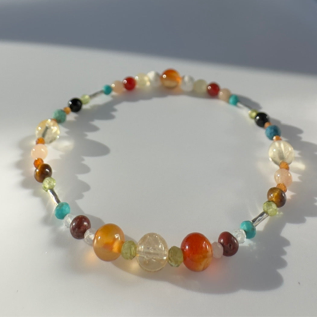 Beaded bracelet in orange yellow and blue tones on a pale grey background