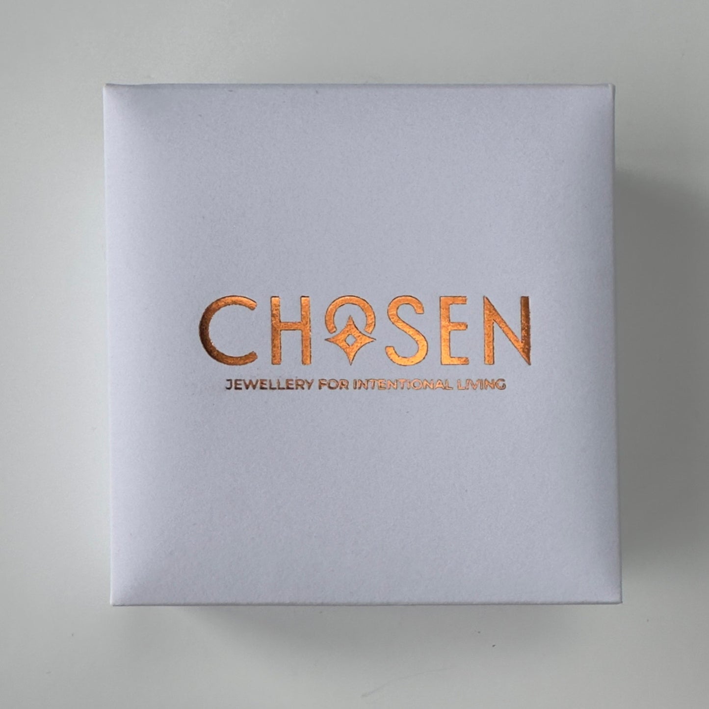 Silver box with 'Chosen' logo in copper on a light gray background