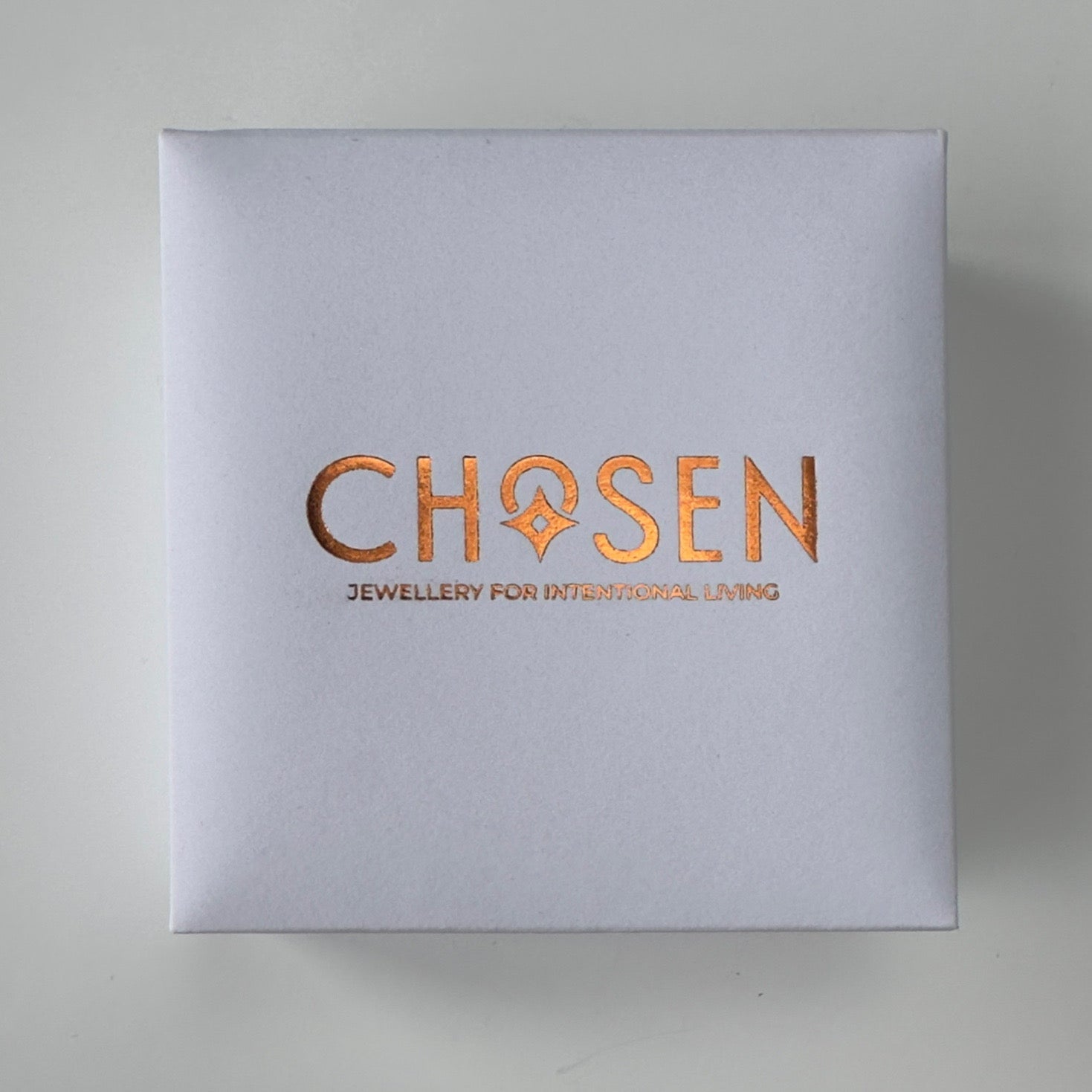 Silver box with 'Chosen' logo in copper on a light gray background