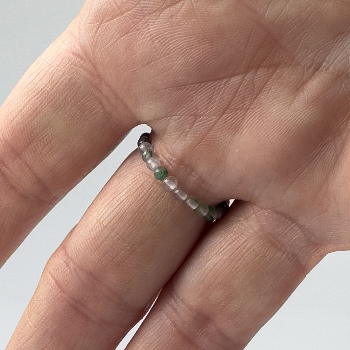 Beaded ring with green and clear beads worn on the finger