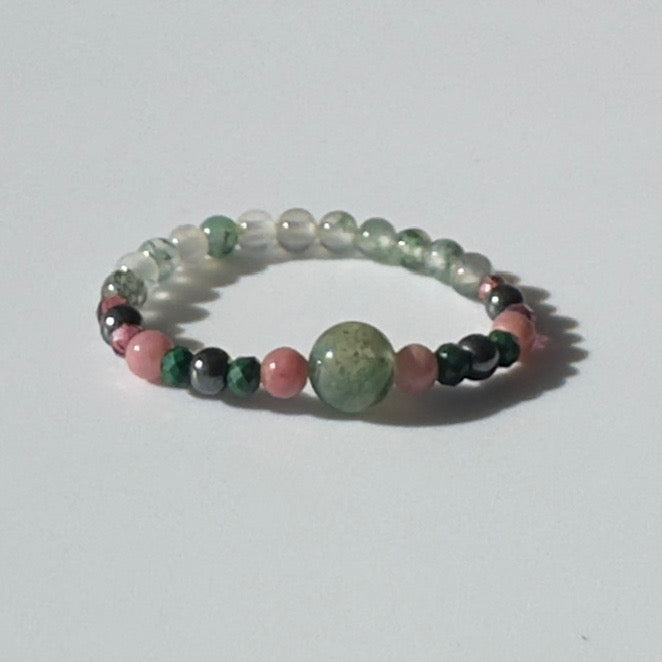 Beaded ring with green, pink, and black beads on a white background