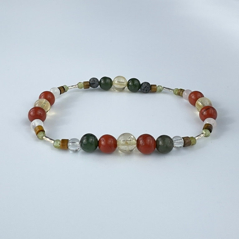 Beaded bracelet in tones of olive red and yellow on a pale grey background