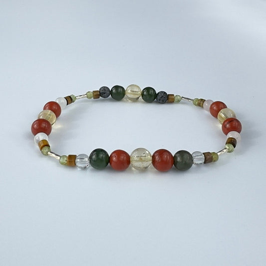 Beaded bracelet in tones of olive red and yellow on a pale grey background