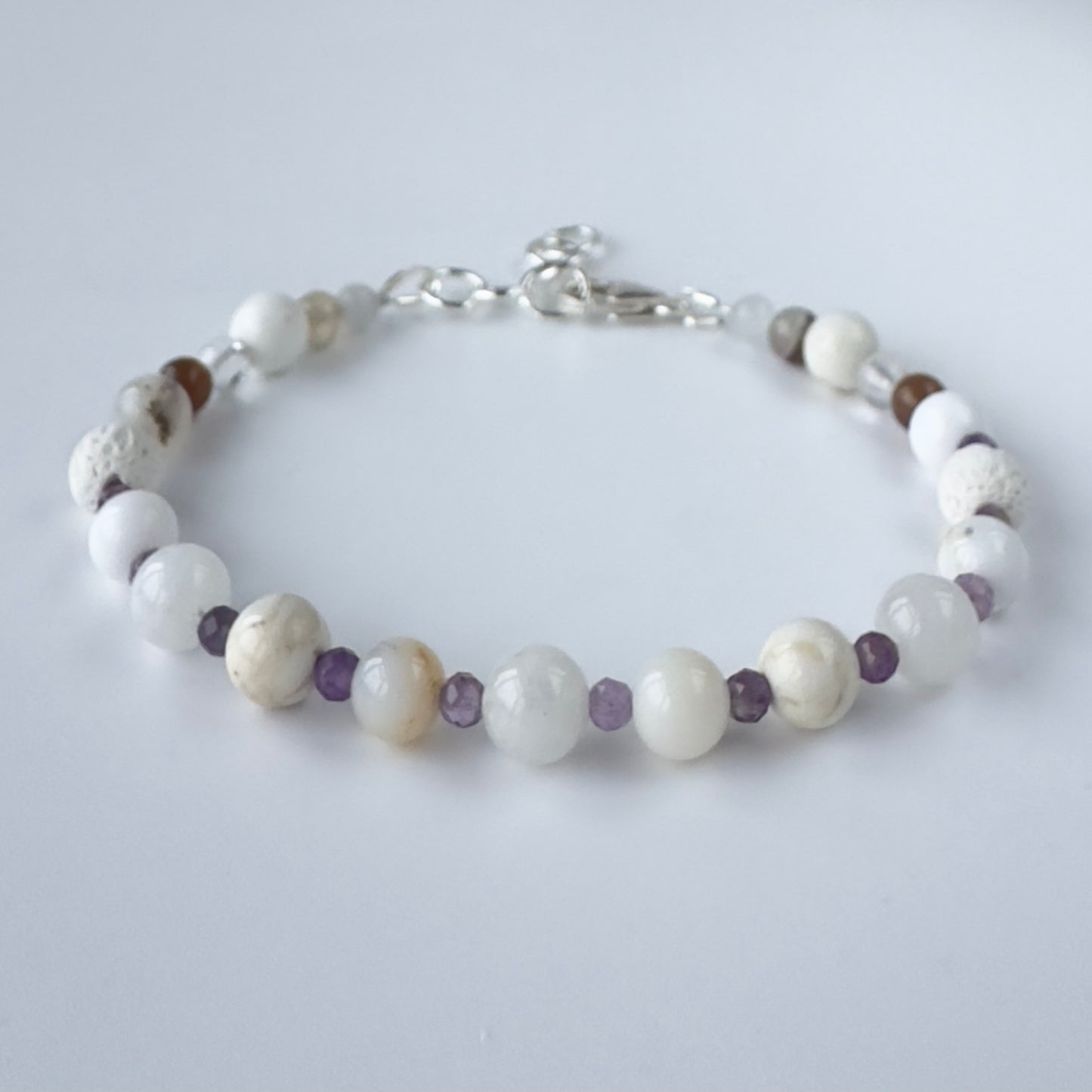 White and purple beaded bracelet on a light grey background