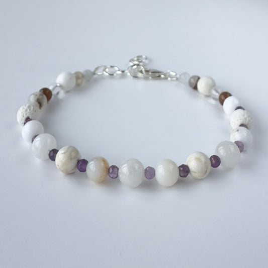 White and purple beaded bracelet on a light grey background