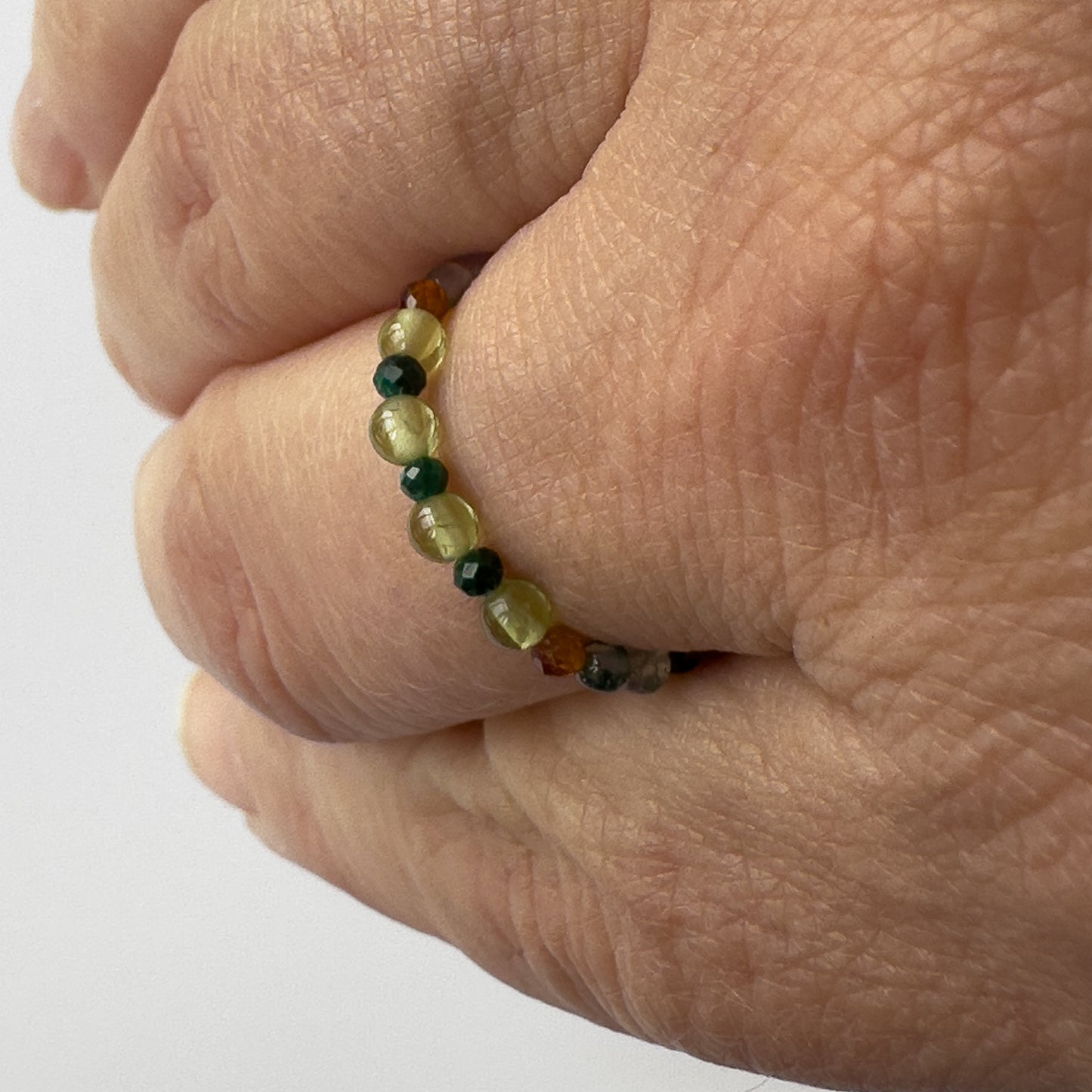Green and orange beaded ring worn on a finger