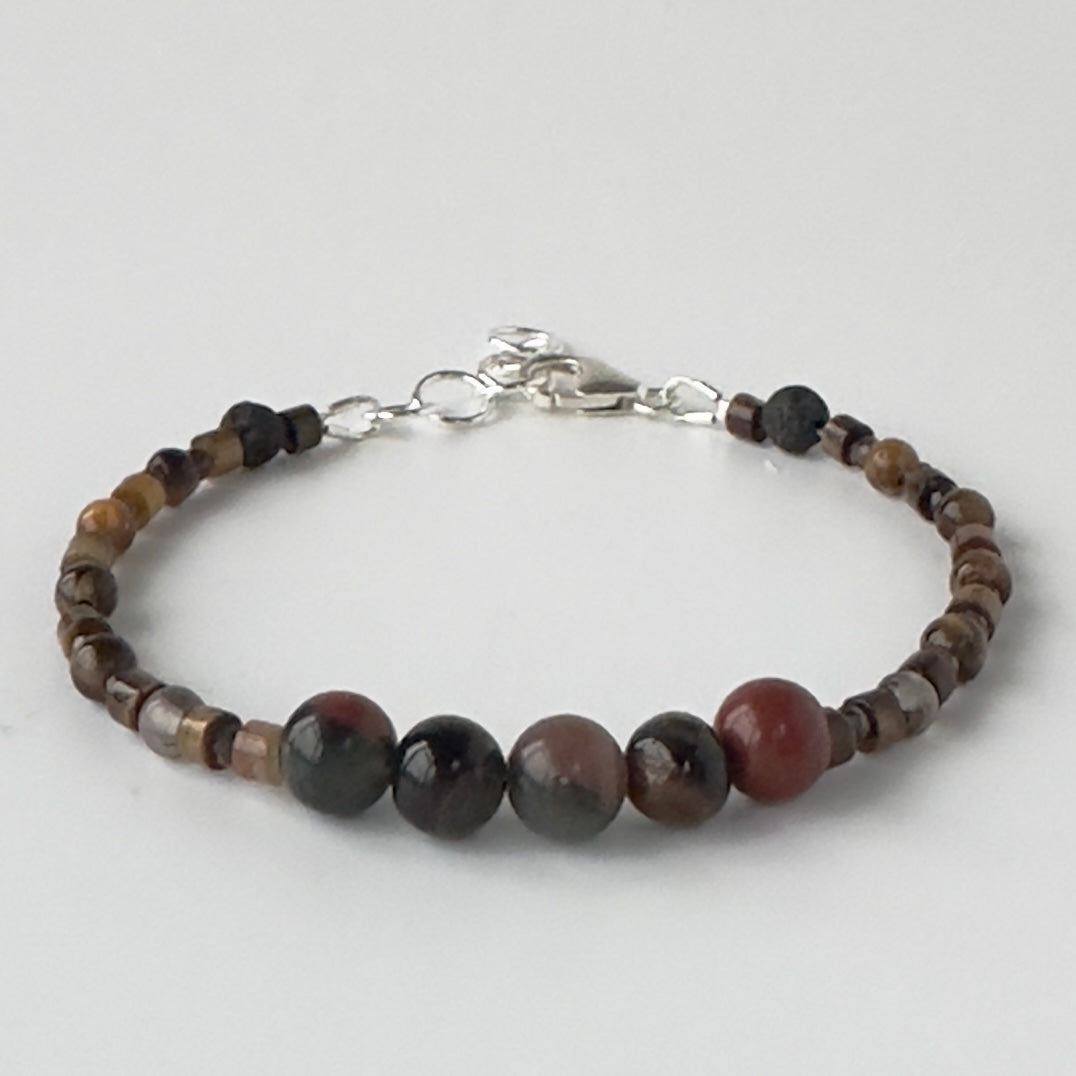 Beaded bracelet in brown tones on a light grey background