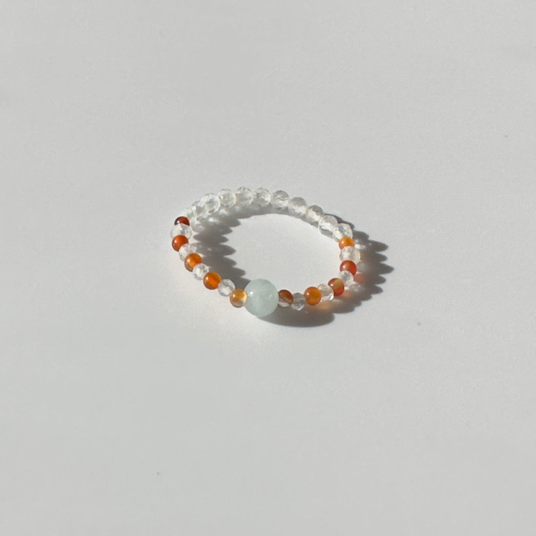 Beaded ring with multicolored beads on a light grey background
