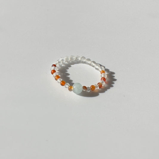 Beaded ring with multicolored beads on a light grey background