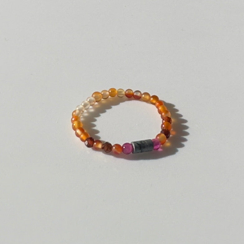 Beaded ring with multicolored beads on a light grey background