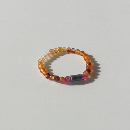Beaded ring with multicolored beads on a light grey background