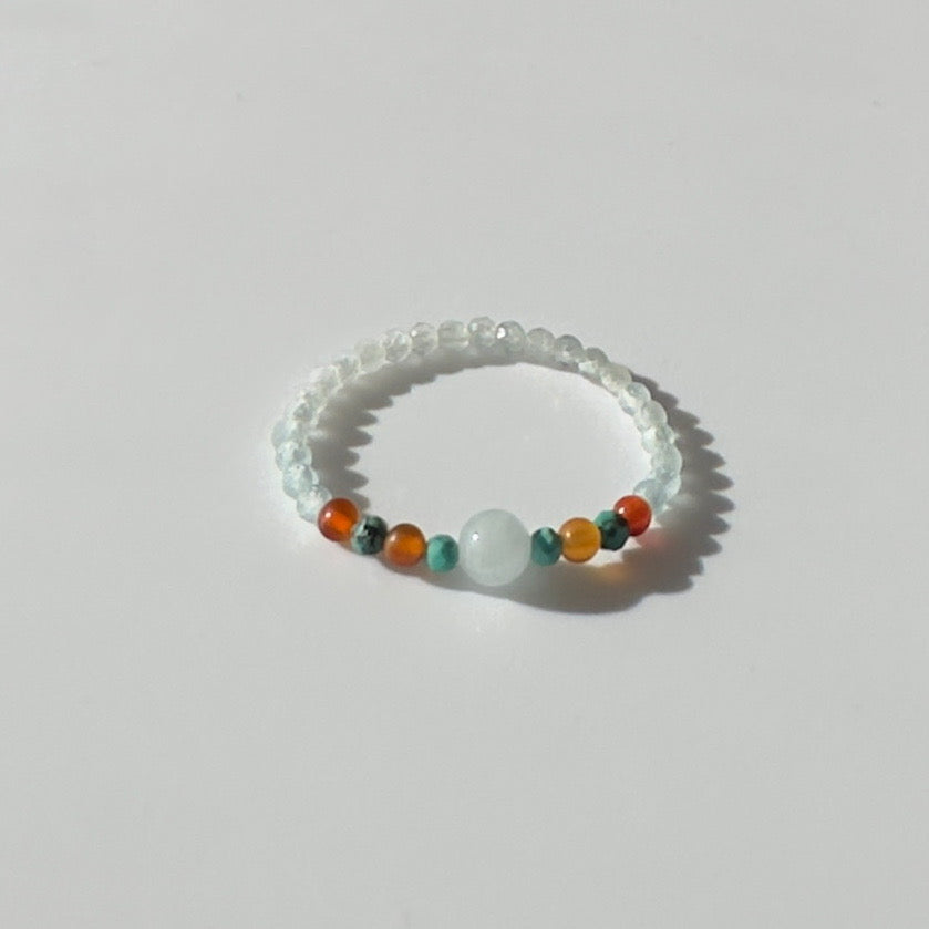 Beaded ring with multicolored beads on a light grey background