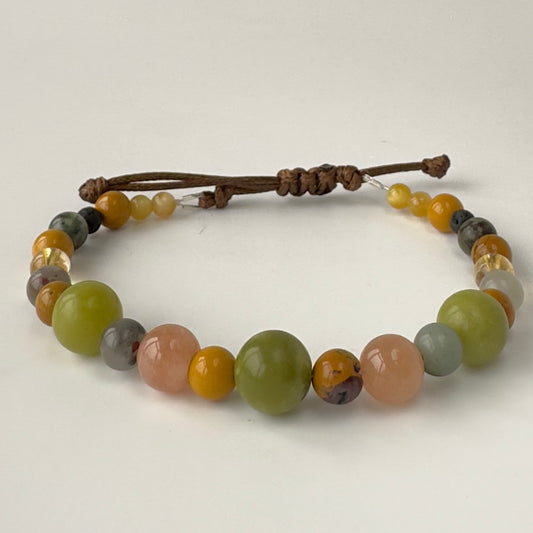 Beaded bracelet in shades of green and brown on a white background
