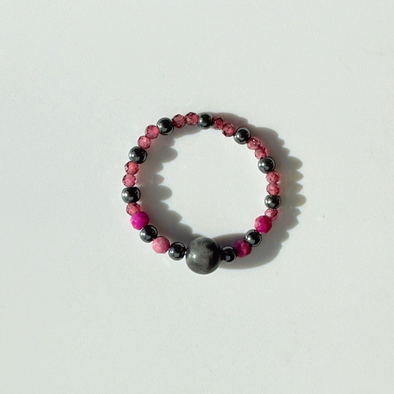 Beaded ring with pink and grey beads on a white background