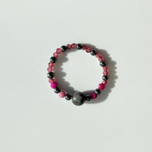 Beaded ring with pink and grey beads on a white background
