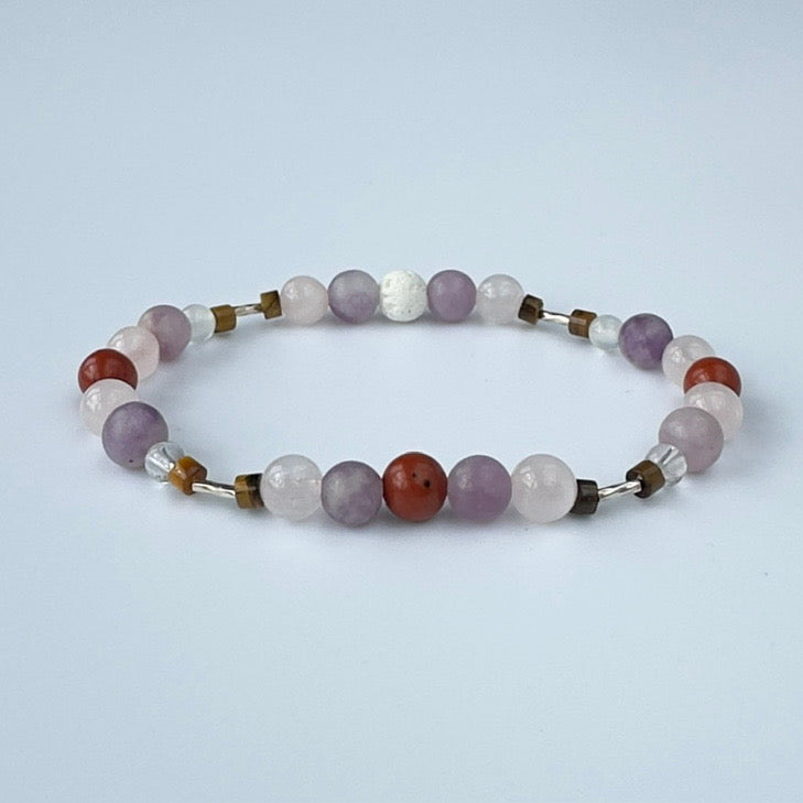 Beaded bracelet in tones of lilac red and brown on a pale grey background