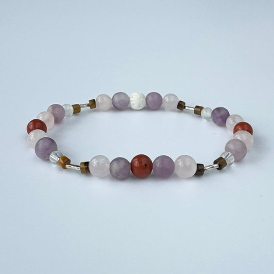 Beaded bracelet in tones of lilac red and brown on a pale grey background
